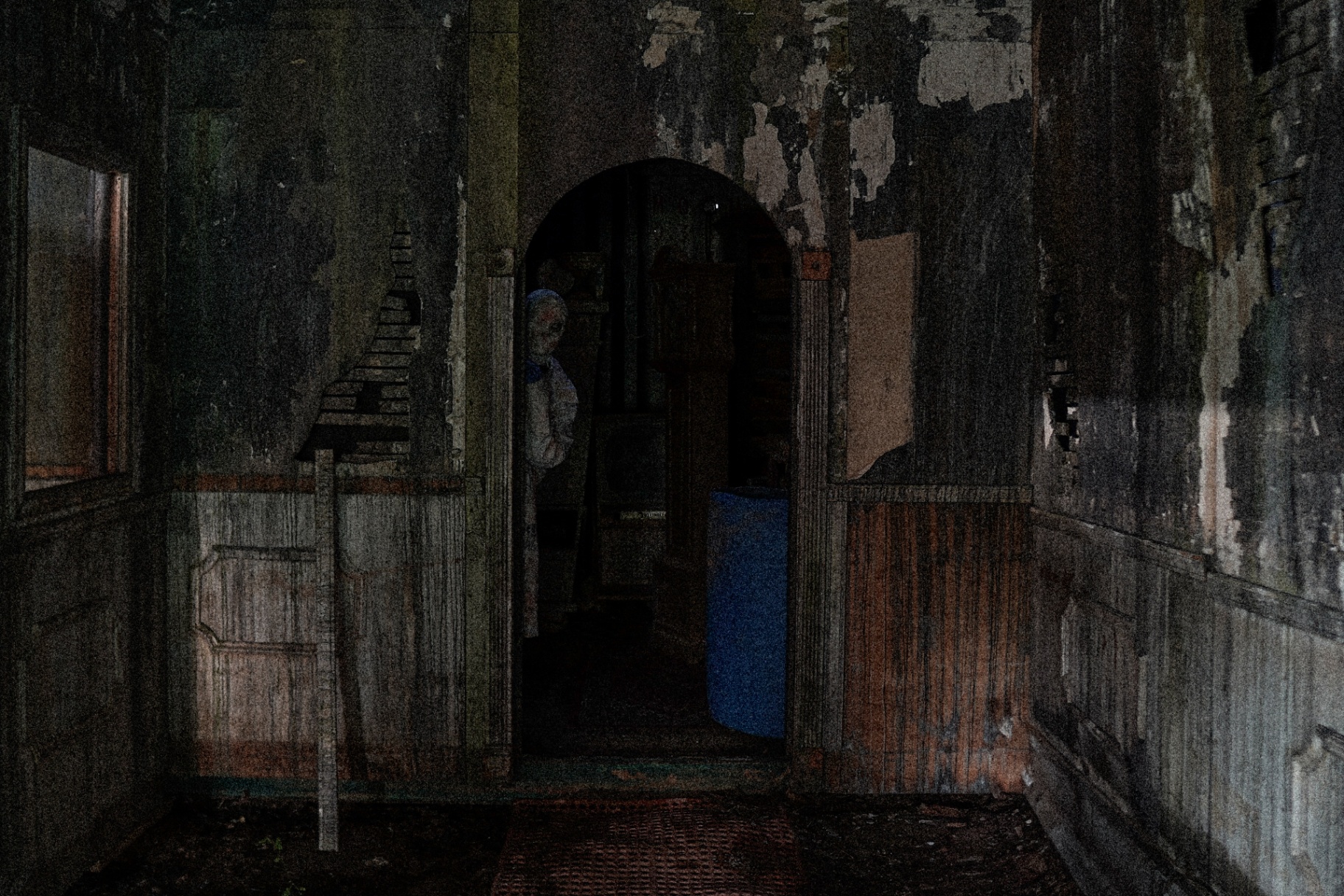 Decayed interior room with masked figure in archway